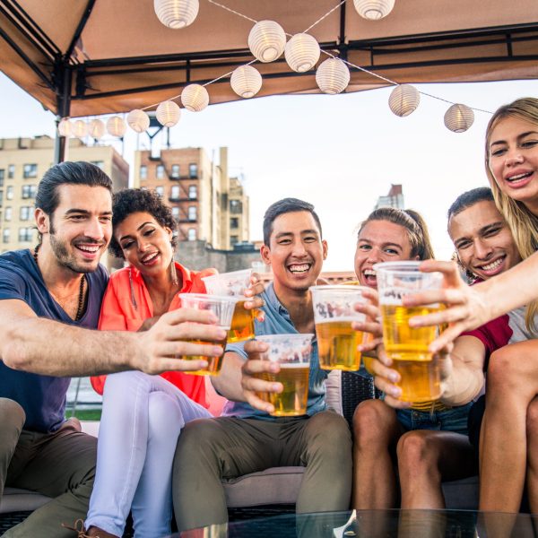Young happy people having a barbecue dinner on a rooftop in New York - Group of friends having party and having fun